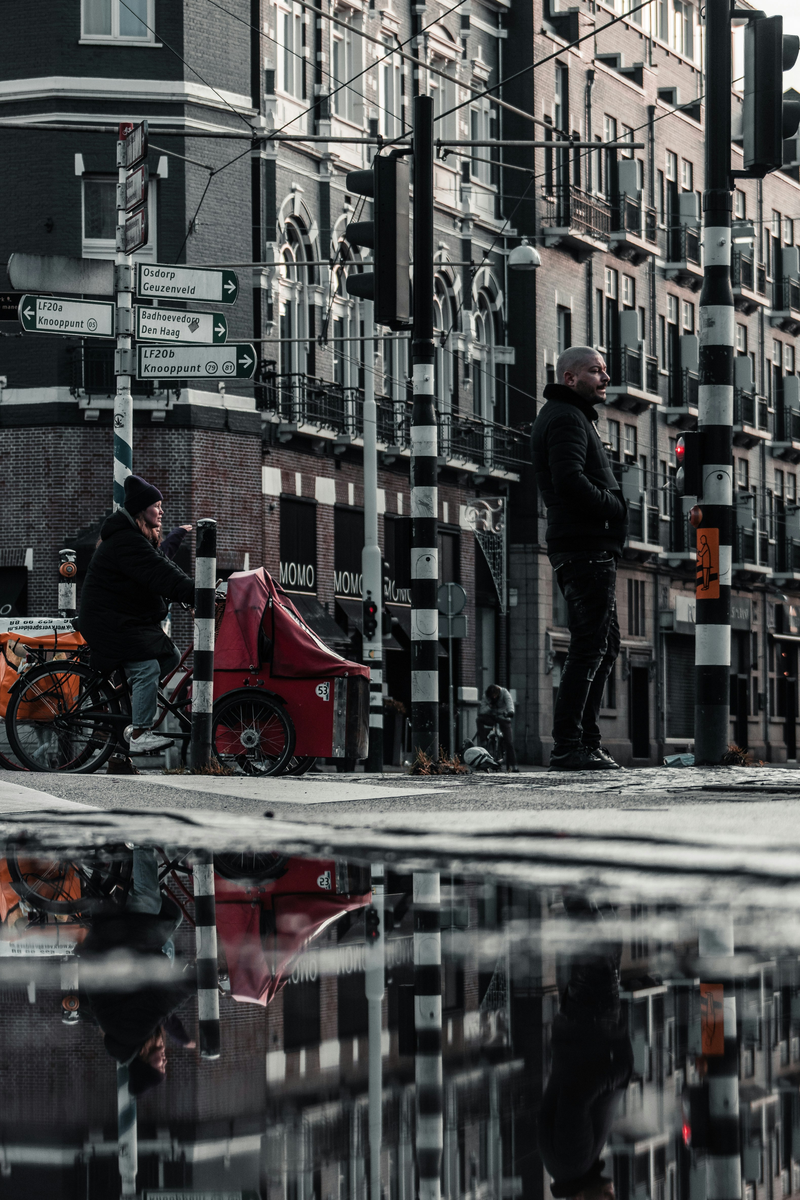 man in black jacket and black pants standing on sidewalk during daytime